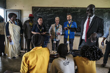 FAO/IFAD/PAM/Eduardo Soteras. Au centre, de gauche à droite : Le Directeur général de la FAO, QU Dongyu, la Directrice exécutive du PAM, Cindy McCain, et le Président du FIDA, Alvaro Lario, discutent avec les élèves d'une classe lors d'une visite à l'école primaire d'Udhaba, dans le village d'Udhaba, dans le cadre de la visite officielle des directeurs des agences basées à Rome au Sud-Soudan. 